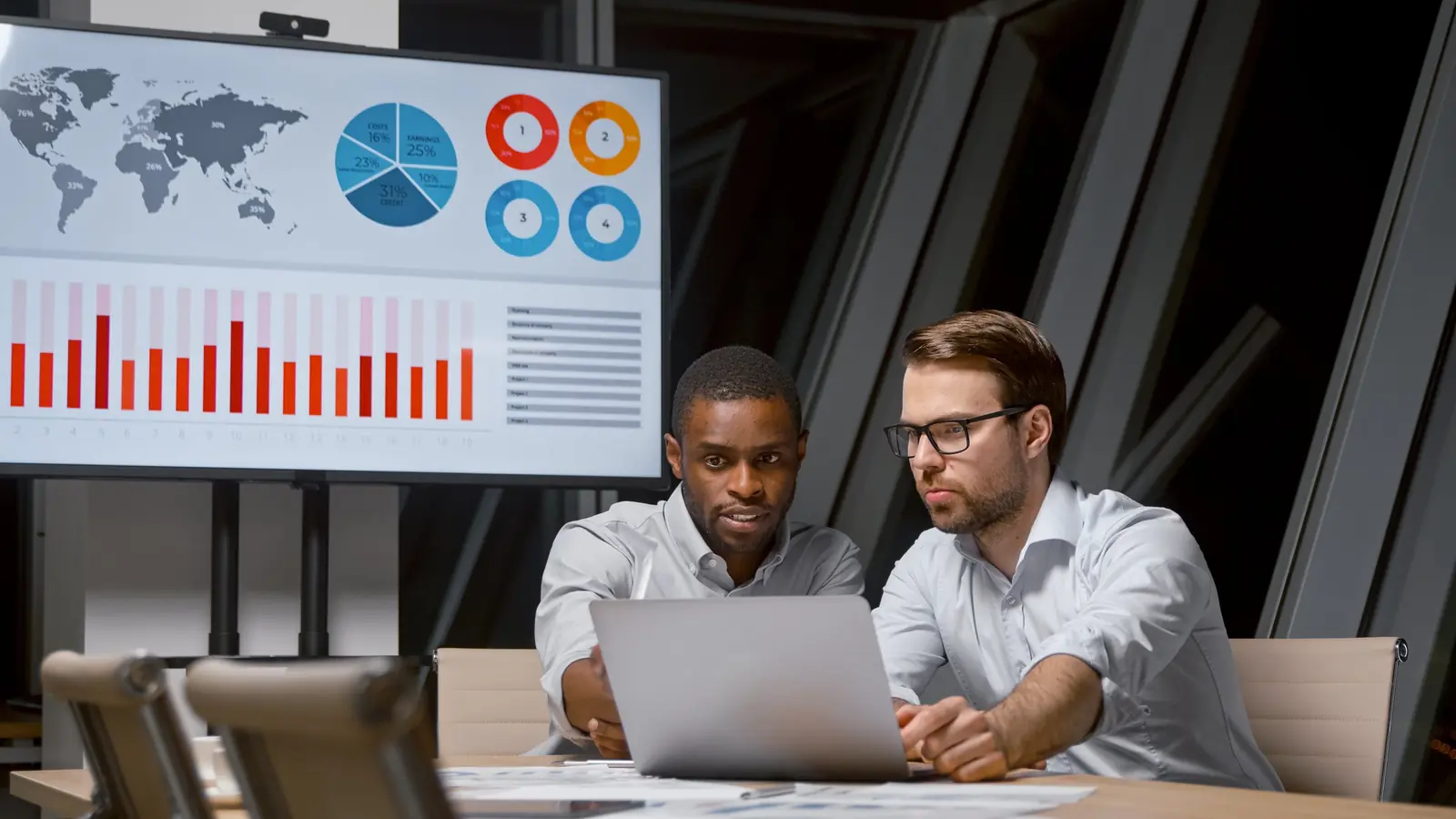 Two colleagues planning a campaign in front of a board of growth charts